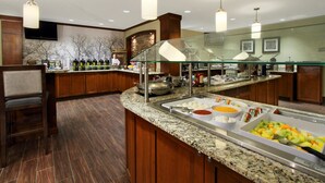 A buffet area with a variety of food items, a glass partition, and wooden cabinetry. - Great Value! Cozy 2 Bedroom Suite in Mclean | Free Breakfast + 24h Business Center (McLean)