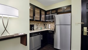 A compact kitchen with dark cabinets, stainless steel appliances, and a modern light fixture. - Great Value! Cozy 2 Bedroom Suite in Mclean | Free Breakfast + 24h Business Center (McLean)