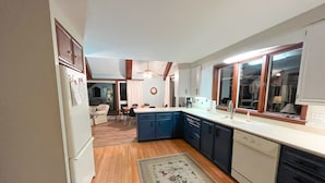 Une cuisine compacte avec un plancher en bois, un îlot central et un coin repas à l’arrière-plan.