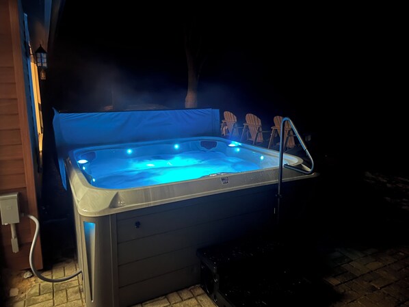 Ett bubbelbad med inbyggd värmare och en stege, omgivet av en uteplats med ett stengolv.