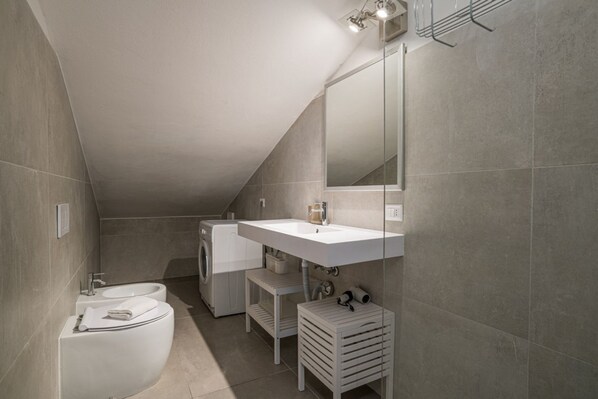 A modern bathroom with a built-in washing machine, a sink, and a toilet.