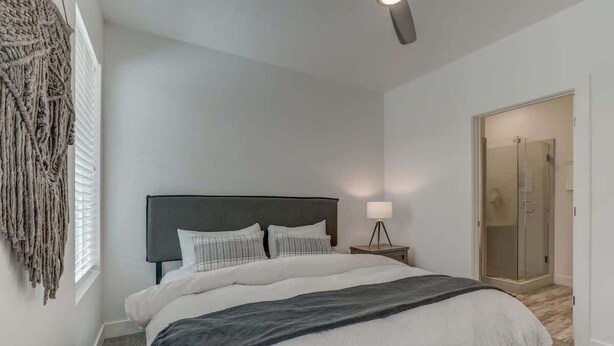 A bedroom with a bed, bedside lamp, and a door leading to a bathroom. - Pool View | Bunk Beds | Fast Internet | Loft 32 (Saint George)