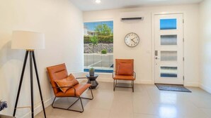 A modern interior with two leather chairs, a floor lamp, a clock, and a door with frosted glass panels. - Pool View | Bunk Beds | Fast Internet | Loft 32 (Saint George)