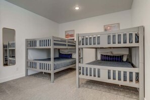 Ein Zimmer mit drei Etagenbetten, einem Spiegel und einem gerahmten Bild an der Wand.