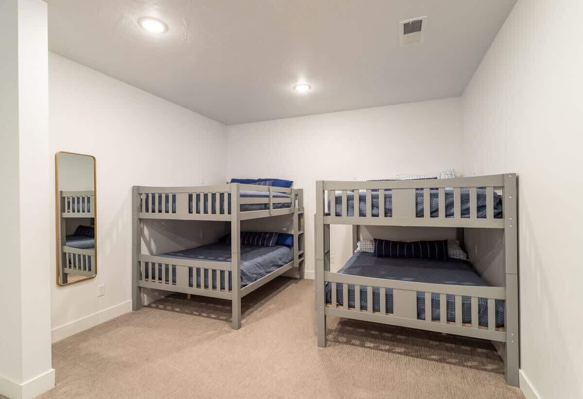 A room with bunk beds, a mirror, and a carpeted floor.