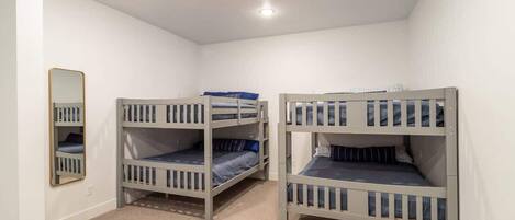 A room with bunk beds, a mirror, and a carpeted floor.