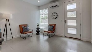 A room with two leather chairs, a floor lamp, a clock, and a door with frosted glass panels. - Pool View | Bunk Beds | Fast Internet | Loft 32 (Saint George)