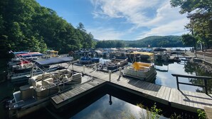 A marina with various boats docked, surrounded by lush greenery and hills in the background.