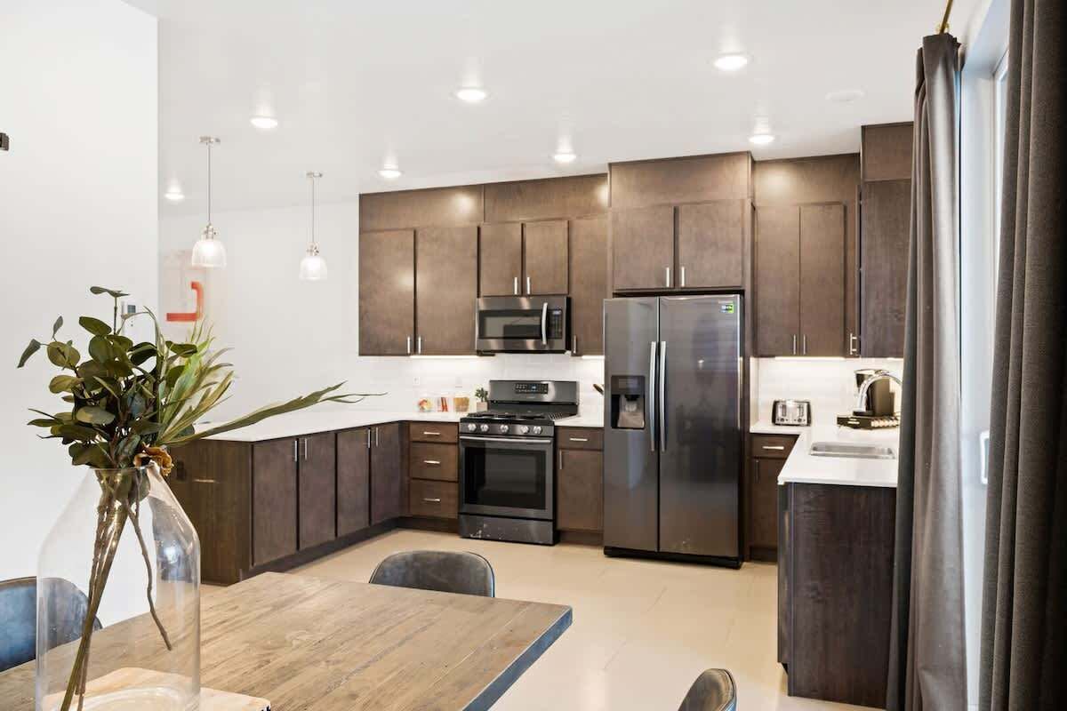 A modern kitchen with dark cabinetry, stainless steel appliances, and pendant lighting.