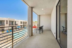 A balcony with a view of a swimming pool and adjacent buildings.