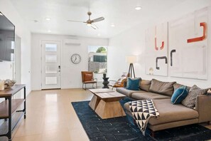 A spacious living room with a sofa, coffee table, and a ceiling fan.