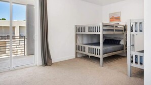A room with a bunk bed, a sliding glass door leading to a balcony, and a painting on the wall. - The Lofts #33 | Townhome Pool Resort | Poolside (Saint George)