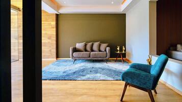Una sala de estar moderna con un sofá, un sillón color turquesa y una alfombra estampada.
