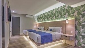 Una habitación de hotel moderna con una cama grande, mesitas de noche y una pared con diseño de hojas.