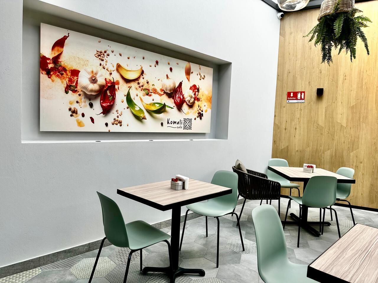 Un restaurante con una decoración moderna, que presenta una gran obra de arte culinaria, varias mesas con sillas y una pared de acento de madera.