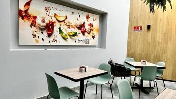 Un restaurante con una decoración moderna, que presenta una gran obra de arte culinaria, varias mesas con sillas y una pared de acento de madera.