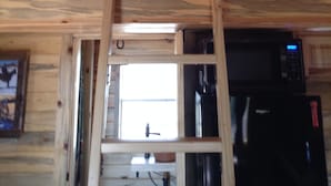 Techo de madera con una viga central y una ventana que ofrece vistas a un edificio.