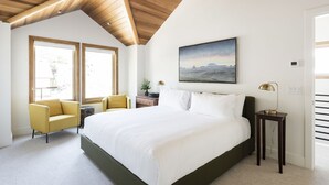 Una camera da letto con un letto grande, una poltrona gialla, un comodino e un quadro appeso al muro.