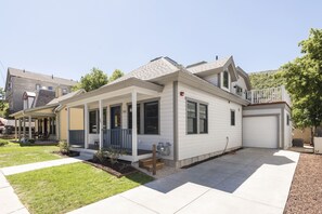 Een gelijkvloers huis met een overdekte veranda, een garage en een verzorgd gazon.