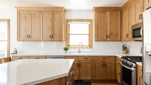 Una cucina moderna con mobili in legno, piano cottura in acciaio inossidabile e una grande isola.