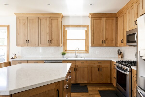 A modern kitchen with wooden cabinets, a stainless steel stove, and a large island.
