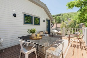 Een terras met een tafel, stoelen, een potplant en een kan limonade.