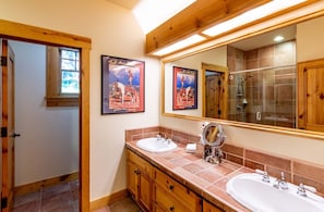Ein Badezimmer mit zwei Waschbecken, Holzschränken, einem großen Spiegel und zwei Bildern an der Wand.