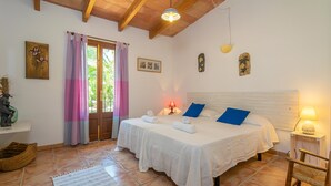 Une chambre avec deux lits, un plafond en bois, une fenêtre avec des rideaux et une petite table de chevet avec une lampe.