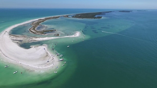 Luftaufnahme einer Küstenregion mit klarem Wasser, Sandstränden und Booten.