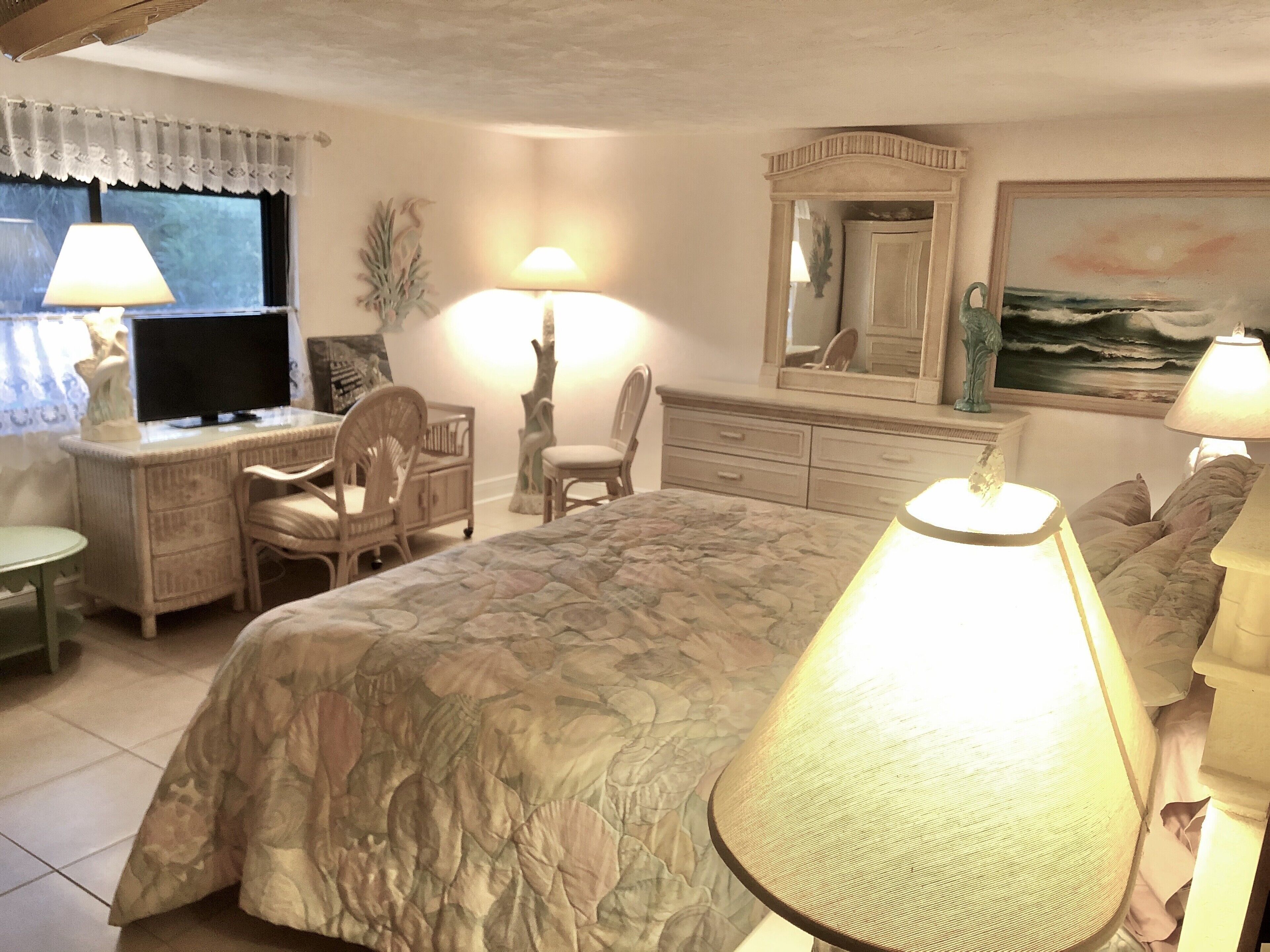 A bedroom with a bed, desk, chair, dresser, and a painting on the wall.