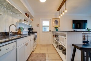 A kitchen with white cabinetry, a granite countertop, a built-in oven, and a hanging light fixture.