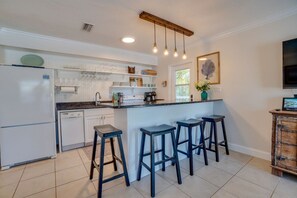A kitchen with a white refrigerator, white cabinets, a black countertop, and three blue bar stools.
