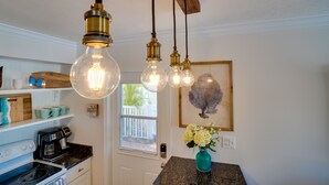 A kitchen with a white door, a coffee maker, a stove, and hanging light fixtures.