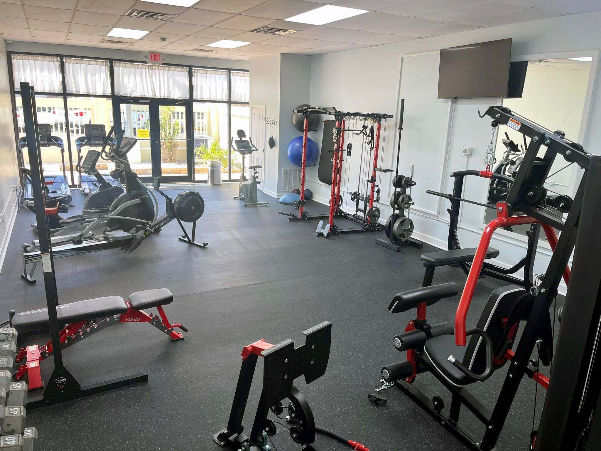 Un gimnasio con máquinas de cardio, equipo de levantamiento de pesas y pelotas de ejercicio.