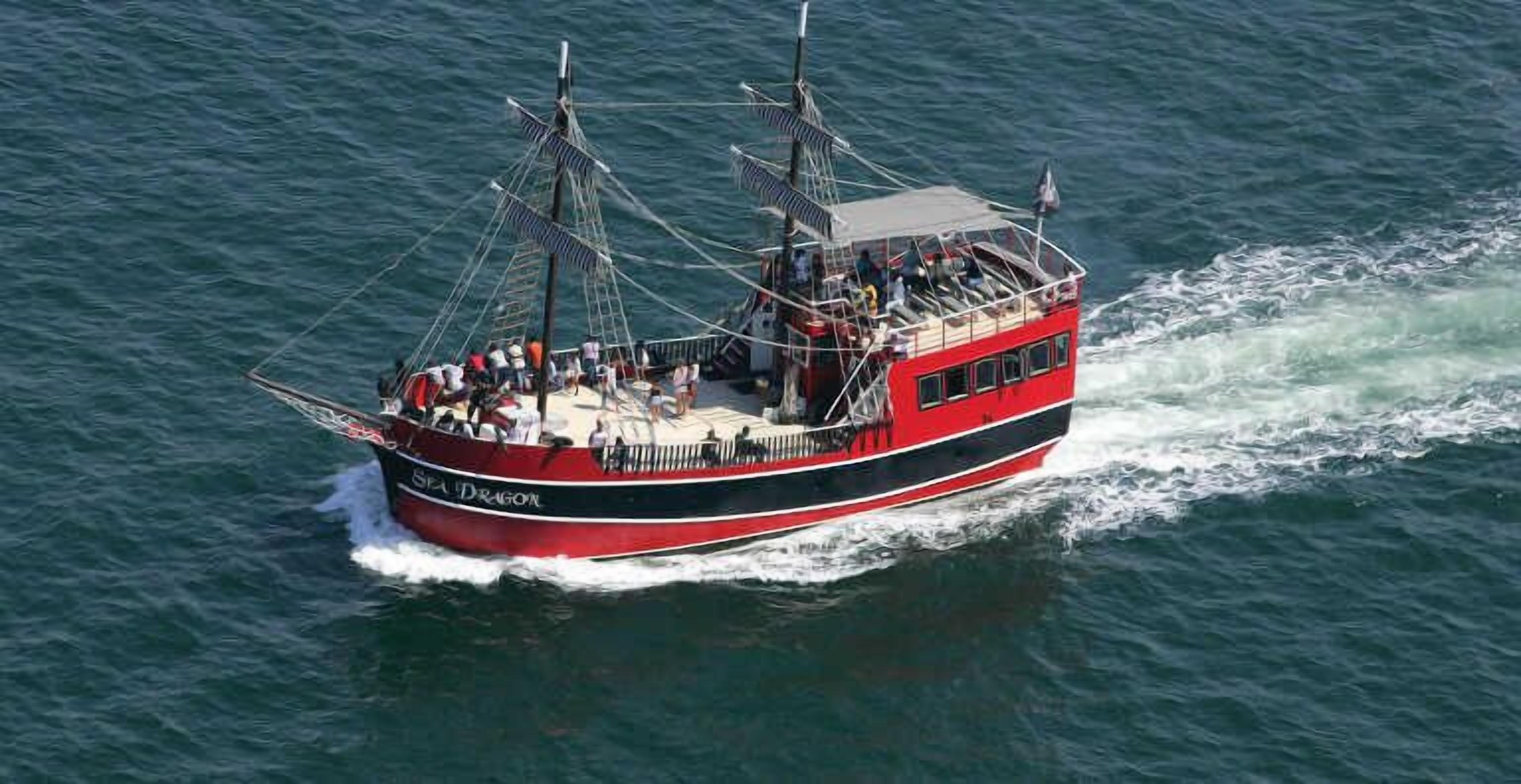 Un bateau rouge et noir nommé « SEA DRAGON », doté de plusieurs ponts et transportant des passagers.