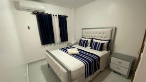 A bedroom with a bed, nightstand, and a small drawer unit. - Residencial Palma Real (Puñal)