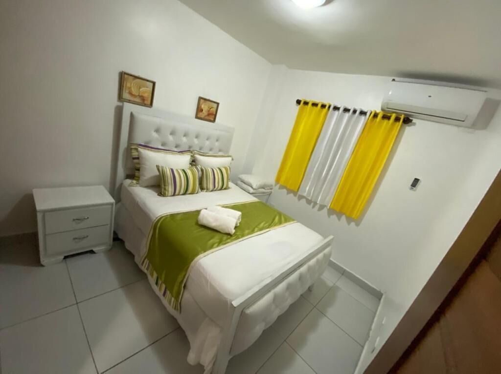 A bedroom with a bed, nightstand, and air conditioning unit.