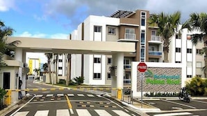 A gated entrance to a modern building with a clear pedestrian crossing and a stop sign. - Residencial Palma Real (Puñal)