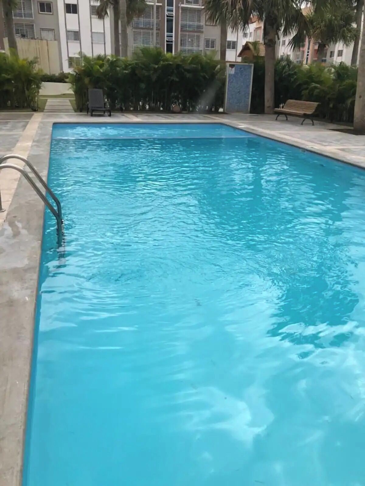 A rectangular swimming pool with clear blue water, surrounded by a concrete deck.