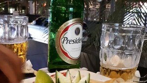 Ein Tisch mit einer Speisenplatte, einer Bierflasche und zwei Biergläsern.