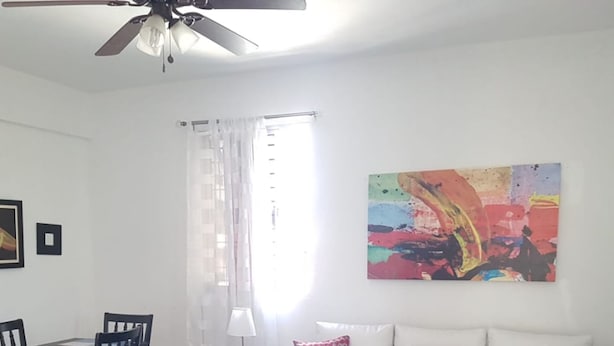 Ein modernes Wohnzimmer mit einem weißen Sofa, einem Glastisch und einem Essbereich mit Stühlen und einem Tisch.