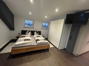Een moderne slaapkamer met een groot bed, twee nachtkastjes, een kledingkast en een televisie.
