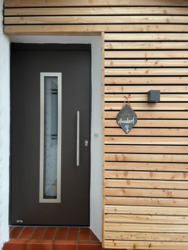 A modern door with a vertical glass panel and a handle, a small mailbox, and a sign reading "Abergroft" on a wooden wall. - Abendrot Apartment - Ennerla-Hof (Pottenstein)