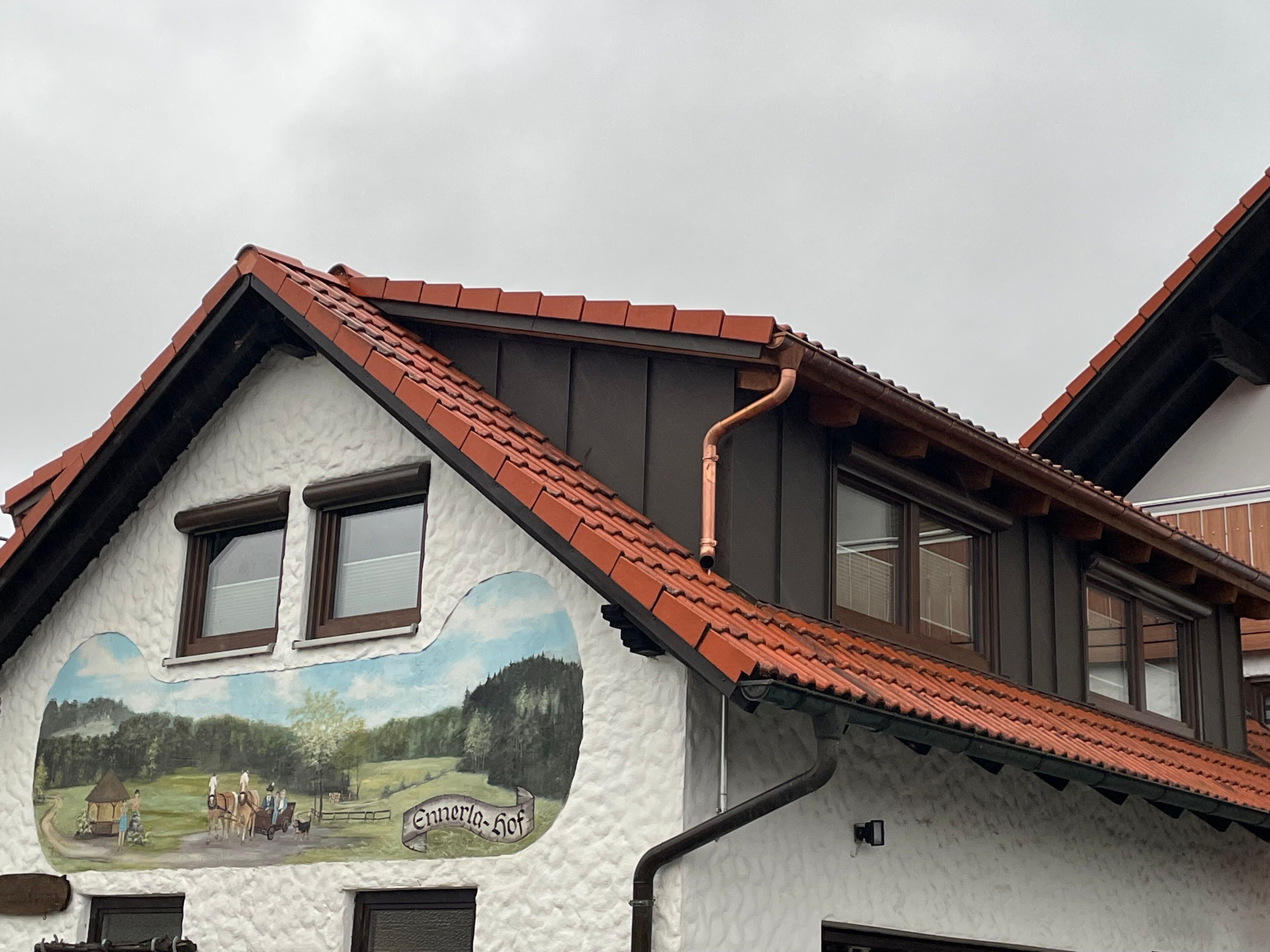 Un bâtiment orné d’une fresque représentant un paysage rural et portant l’inscription « Ennerhof ».