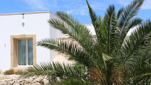 A modern building with a white facade, a large glass door, and a stone base. - trullomio.com - Villa Swimming Pool, BBQ, Trullo, Sea view, WiFi (Torre Suda)
