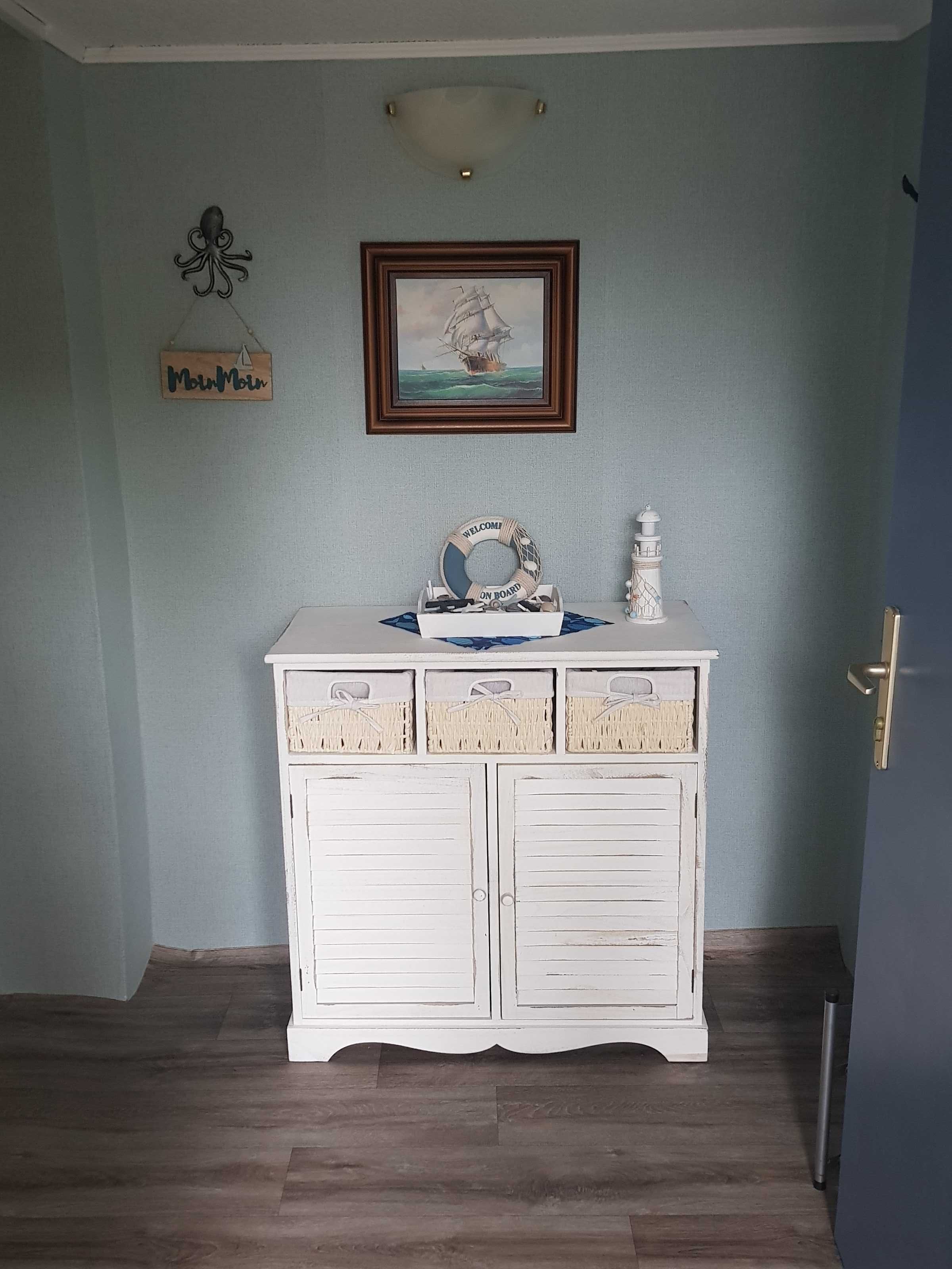 A room with a white cabinet, a framed painting, a welcome sign, and a decorative octopus on the wall.