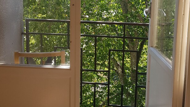 Una habitación con puerta de vidrio corredera que da a un balcón con barandilla de metal.