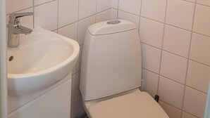 Un baño pequeño y limpio con azulejos blancos, un lavamanos y un inodoro.