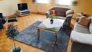 Un salon chaleureux avec un plafond en bois, une télévision, un canapé et une table basse.