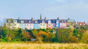 A row of colorful terraced houses with a church steeple in the background. - Alnmouth Close to Beach and golf with Private Parking and Pet Friendly (Alnwick)